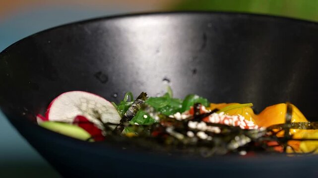 Poke bowl with bright yellow mango cubes, sliced radish, avocado, seaweed, and sesame topping.