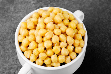 Chickpeas in white bowl on dark background for vegan protein, legume food or healthy eating concept
