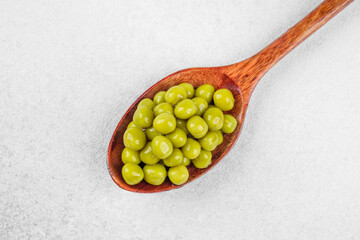 Green peas in wooden spoon on white background for cooking, nutrition or healthy ingredient concept