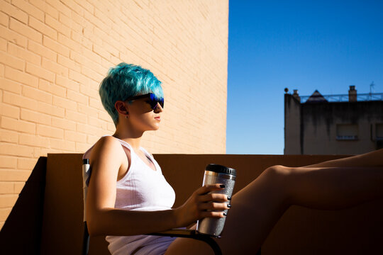Androgyne young woman with blue hair on the balcony
