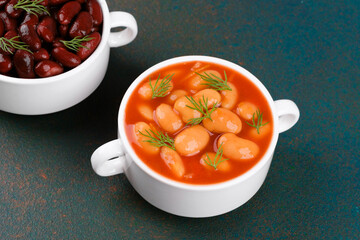 Three types of cooked beans in white bowls on textured table for vegan diet, nutrition or protein food concept