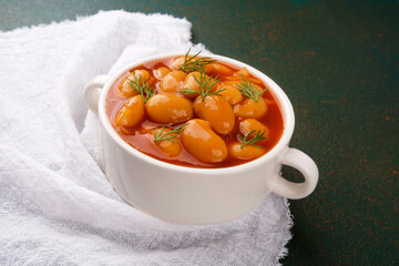 Cooked white beans in tomato sauce with dill in ceramic bowl for vegan meal, lunch or comfort food