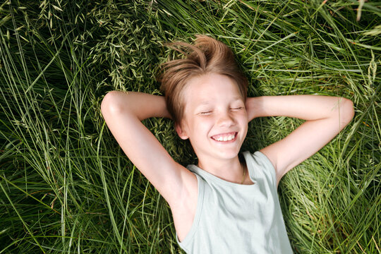 Portrait of happy boy with eyes closed lying on a meadow in summer