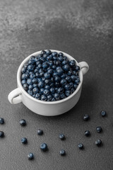 Blueberries with scattered berries on grey for healthy snack or food styling concept