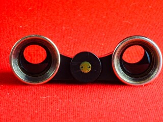 Vintage black theatre binoculars with a lenses on a red background. Made in USSR. 1960s.