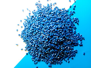 Blue plastic pellets, polymer masterbatch pellets carrying blue pigment, isolated on blue and white...
