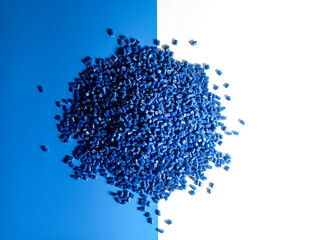 Blue plastic pellets, polymer masterbatch pellets carrying blue pigment, isolated on blue and white...