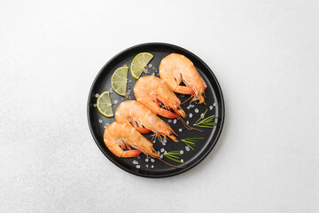 Cooked shrimps with lime rosemary and salt on black plate for seafood cuisine or recipe concept