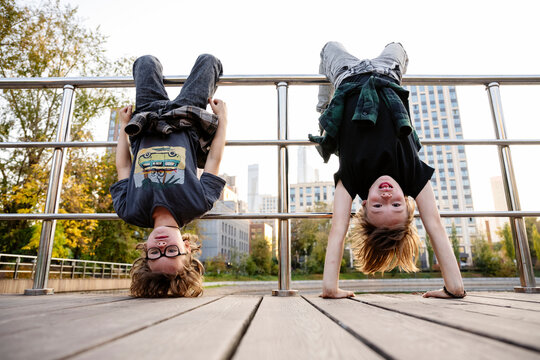 Children hanging upside down from railing