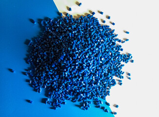 Blue plastic pellets, polymer masterbatch pellets carrying blue pigment, isolated on blue and white...