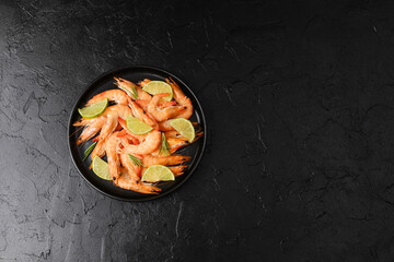 Bowl of cooked shrimp with lime on black background for seafood restaurant or gourmet menu concept