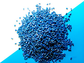 Blue plastic pellets, polymer masterbatch pellets carrying blue pigment, isolated on blue and white...
