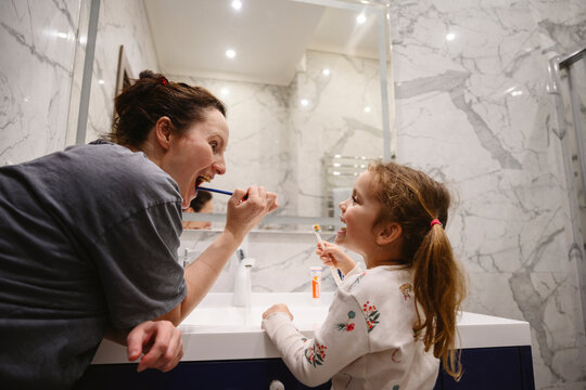 Mother and daughter brushing teeth together in the bathroom