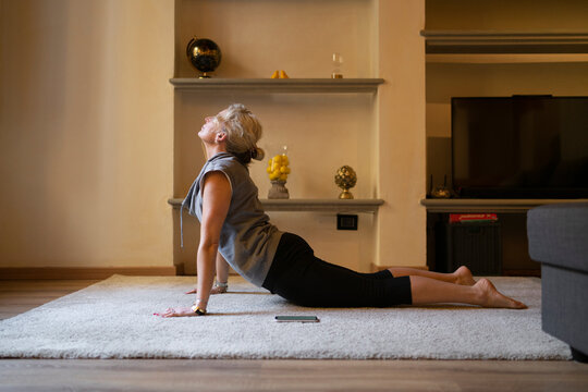Mature woman doing Yoga exercise in the living room