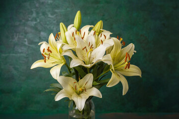 Soft cream lilies bouquet in vases on textured green background – romantic decor or wedding theme