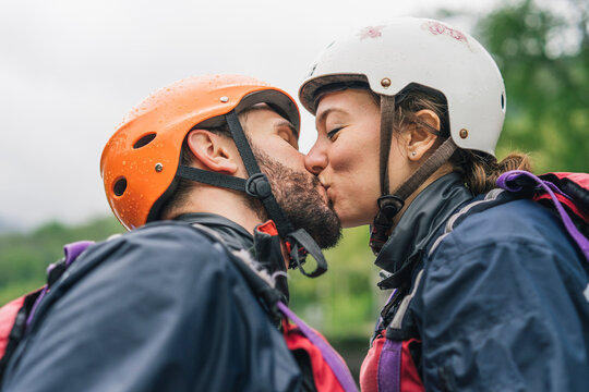 Couple wearing safety helmets kissing outdoors