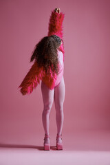 Vertical shot of multiethnic young woman raising right arm upward, wearing fashion forward outfit,...