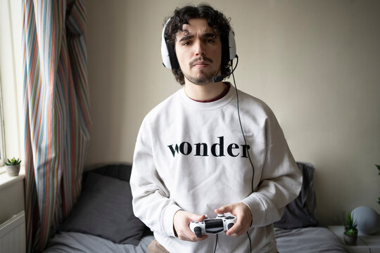 Man with headset holding game controller at home