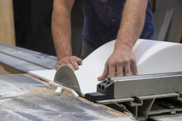 The craftsman cuts and adjusts the size of the acrylic sink with a circular saw