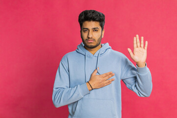 I swear to be honest. Sincere responsible Indian man raising hand to take oath, promising to be...