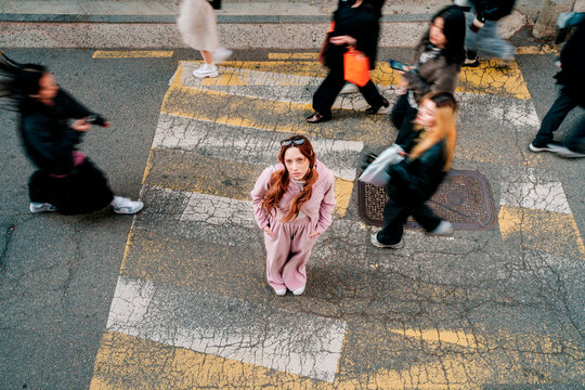Fashionable person standing on urban crosswalk in Seoul surrounded by people
