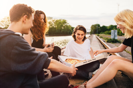 Friends sitting together outdoors sharing a pizza
