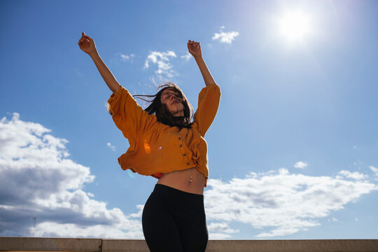 Carefree woman dancing on roof terrace in sunlight