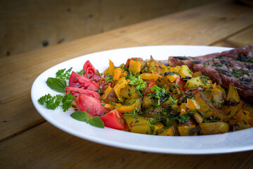 ready to eat - roasted potatoes and aspic with cherry tomatoes and herbs, served on a white plate