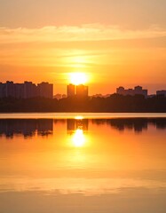 Fototapeta premium Golden sunrise over city reflected in water