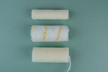 Three paint rollers on green background for painting variety and DIY concept