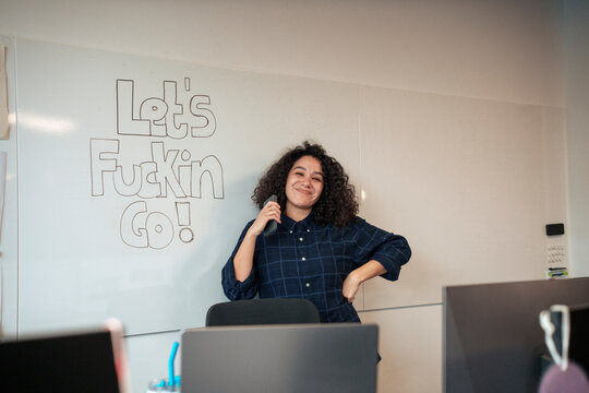 Smiling businesswoman standing near whiteboard in office