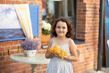 Cute child girl sits in outdoor cafe with oranges fruits. Provence.