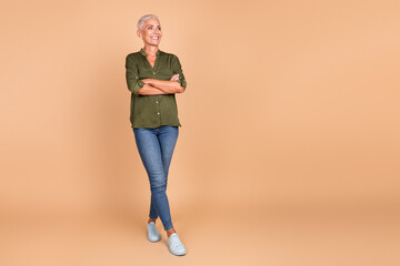 Confident mature woman posing in stylish casual outfit against beige background, embodying charm