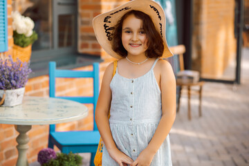 Cute child girl in straw hat in outdoor cafe with oranges fruits. Provence