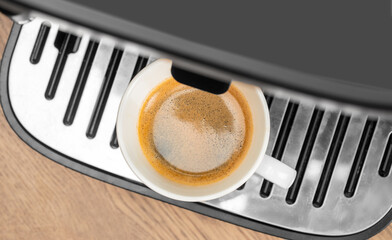 Fresh espresso being brewed into a white cup from a coffee machine. top view. copy space