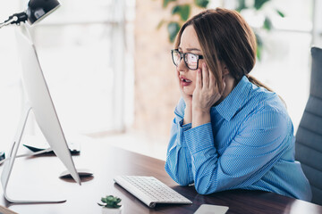 Young businesswoman looking distressed while working at her desktop computer in a modern office environment