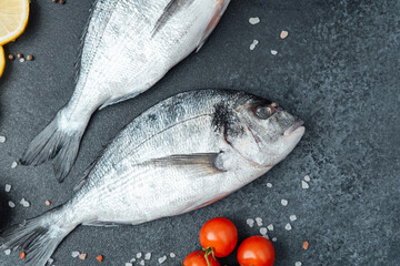 Top view of raw dorado fish with lemon pepper and rosemary on black background