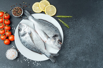 Raw dorado fish with tomatoes lemon herbs and spices on white plate