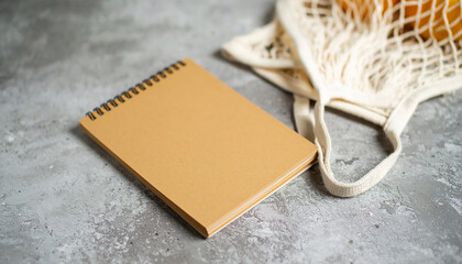 Summer flat lay on a concrete background Peach notepad and an eco-friendly mesh shopping bag