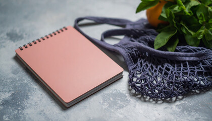 Summer flat lay on a concrete background Peach notepad and an eco-friendly mesh shopping bag