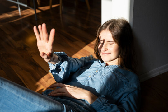 Woman enjoying sunlight indoors with a peaceful expression