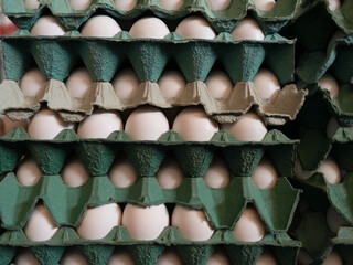 A frame full of chicken eggs in a cardboard box for sale at a market.