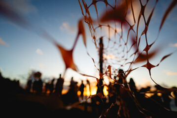 Unidentified people silhouetted through red ribbon fence against dramatic sunset. People on vacation.