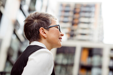 Confident professional woman outdoors in urban street environment with modern buildings, expressing...