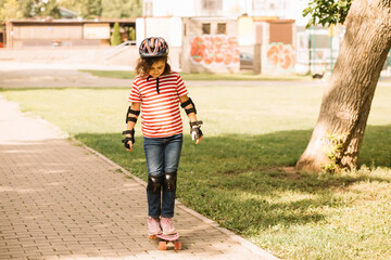 Cute kid girl child riding a skateboard in skatepark. Child performs tricks. Summer sport activity concept. Happy childhood.