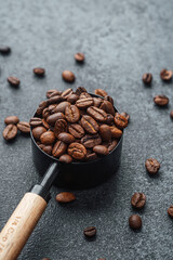 Full measuring spoon of coffee beans on dark background