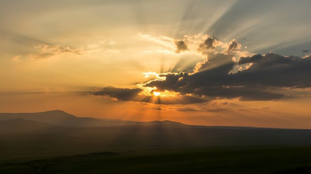Sunbeams breaking through clouds over rolling hills at sunset