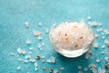 bowl of pink salt with scattered crystals on blue background