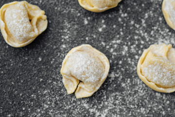 Closeup of scattered flour dusted cappelletti pasta on kitchen counter