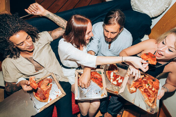Friends enjoying pizza during social gathering at home